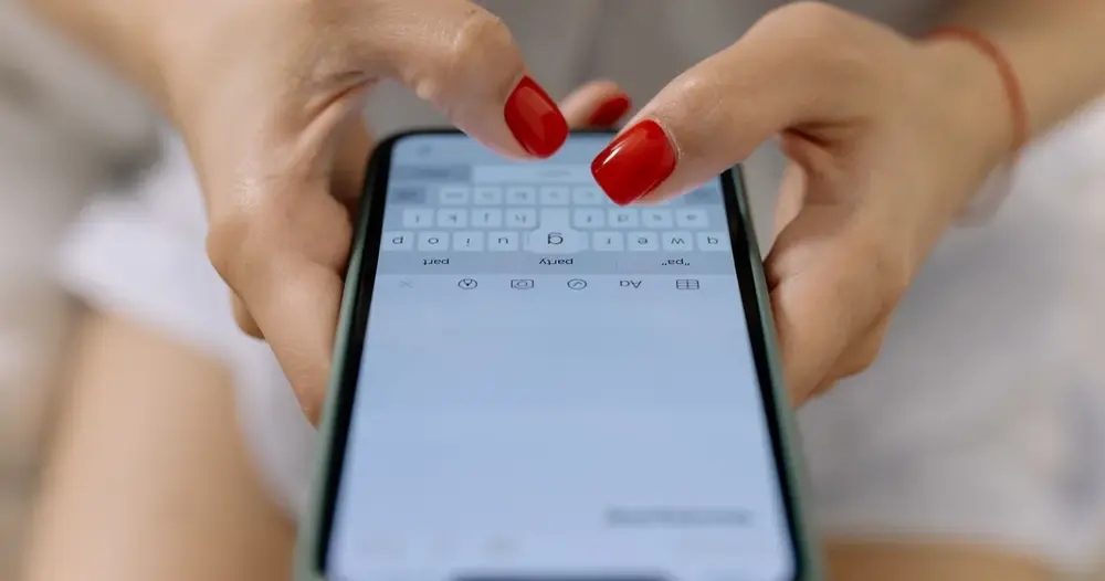 Mãos digitando uma mensagem em um smartphone, ilustrando como pedir um teste IPTV agora